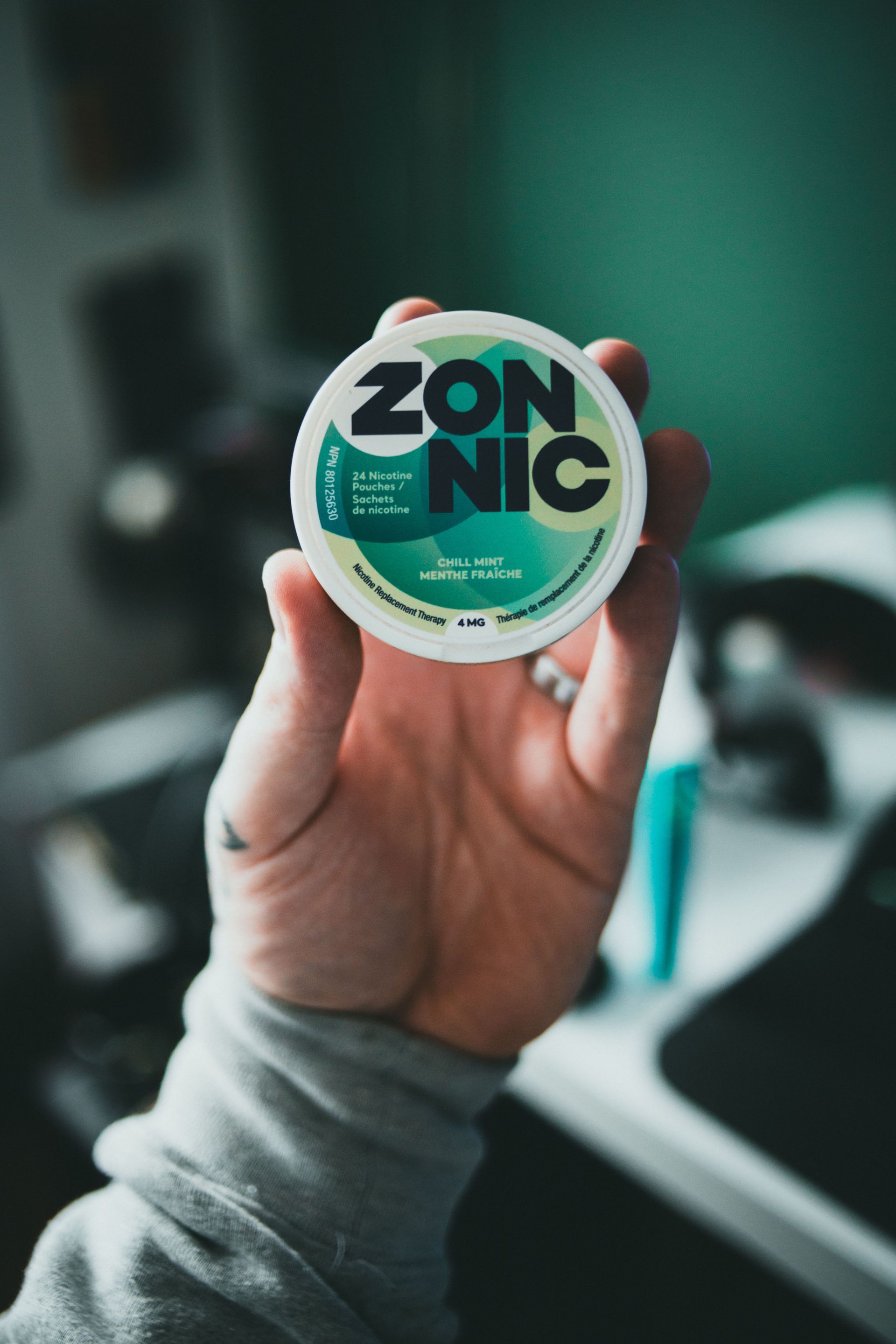 Close-up of a hand holding a ZONNIC nicotine pouch, focusing on the packaging design.